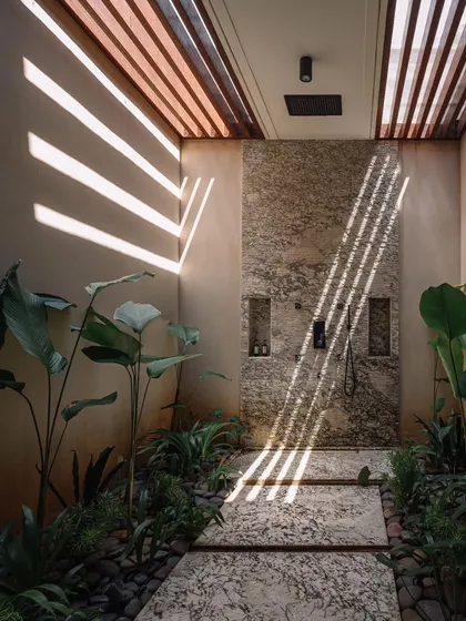 An open-air shower in the GAIA project in Chennai, designed to blend seamlessly with its tropical surroundings. The play of light through the slatted ceiling and the use of natural stone and lush greenery exemplify my approach to creating spaces that feel both luxurious and deeply connected to nature.