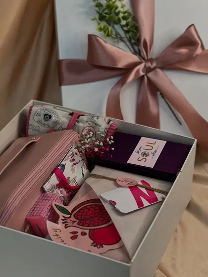 A beautifully curated Women's Day gift box in shades of pink and purple. It includes a personalized pouch, a journal, and other self-care items to make her feel special.