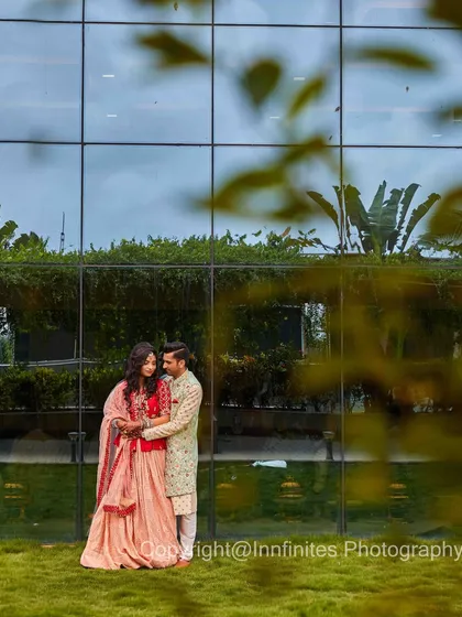 A modern and stylish engagement portrait against a glass-paneled building, capturing the couple in a loving embrace.