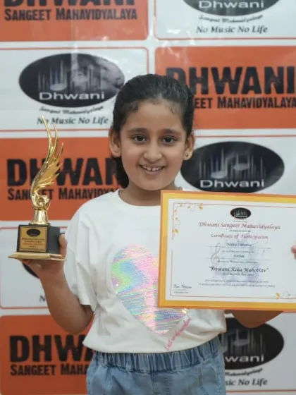 A little girl proudly holds her certificate and trophy.