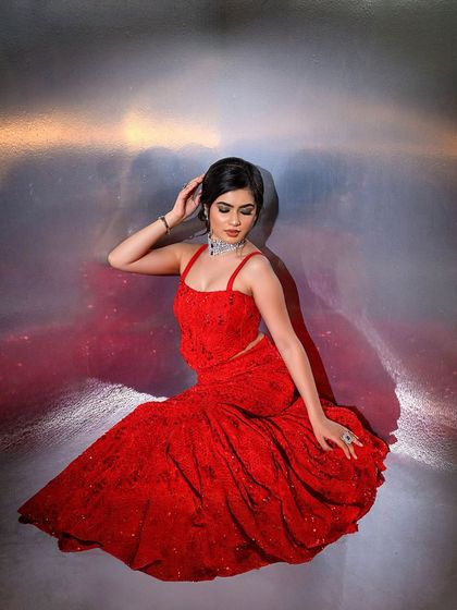 A seated pose in the stunning red gown, showcasing the flow of the fabric and the overall glamorous feel.