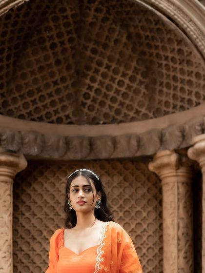 A regal peach-orange silk half saree, embodying a blend of traditional elegance and modern charm. The embroidered organza dupatta adds a layer of sheer beauty.