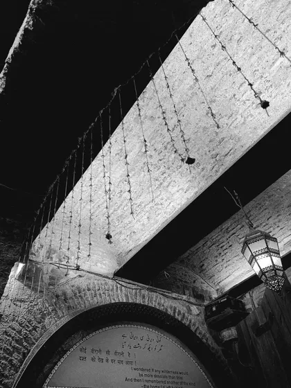 Looking up at an arched ceiling with intricate details and a hanging lantern, a common sight in old structures.