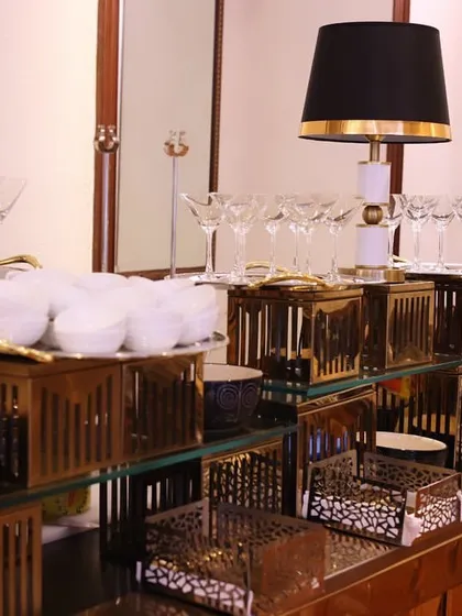 A wide view of our chaat counter, showcasing the meticulous arrangement of bowls, glasses, and serving dishes. The black and gold theme with modern lamps creates a chic and inviting look.