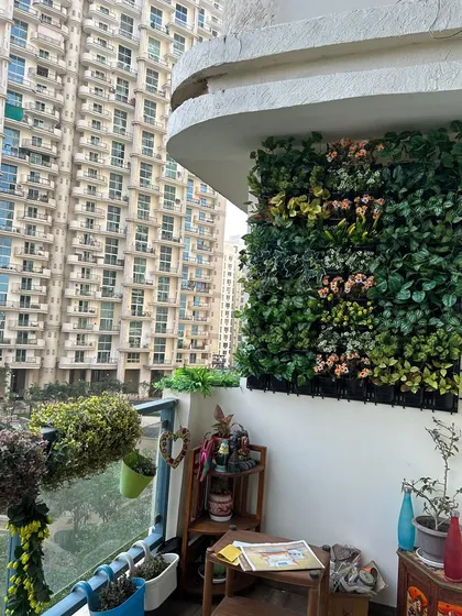 A compact balcony corner is brought to life with a vibrant, multi-colored artificial plant wall, maximizing the small space with greenery.