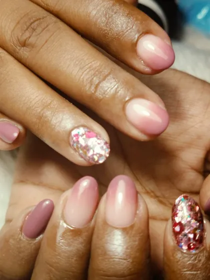 A beautiful pink ombre design on shorter nails, with two accent nails featuring a chunky, iridescent glitter for a pop of sparkle.
