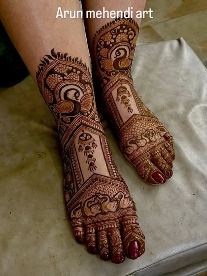 Elegant foot mehendi featuring the graceful Indian peacock. The intricate feathers and patterns cover the feet beautifully.