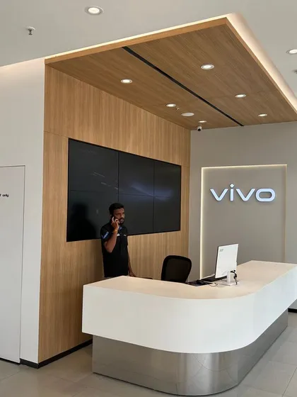 The sleek and modern reception area of the VIVO showroom in Ahmedabad, featuring a minimalist desk, wood-paneled feature wall, and integrated digital screens.
