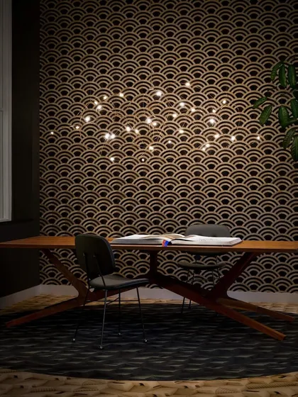 The horizontal version of the Flock of Light, suspended over a desk. The delicate bronze wires trace a path through the air, connecting the small, bright LEDs.