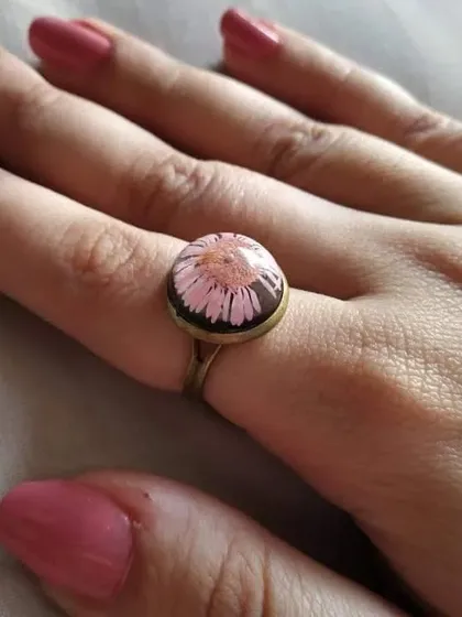 This ethnic-style ring features a beautiful pink pressed flower under a clear dome of resin. The simple, round antique-brass setting gives it a classic, vintage feel.