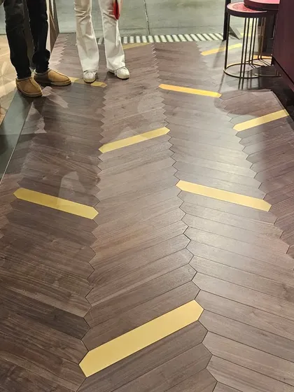 A unique wooden floor design with brass inlay accents, creating a path-like effect. This is the pinnacle of bespoke, luxury flooring.