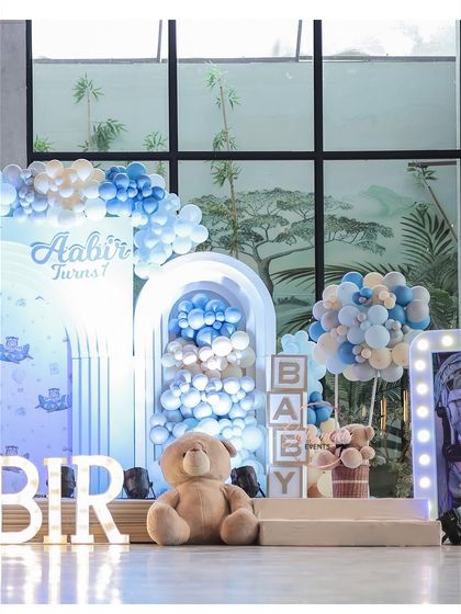 This shot highlights the different elements of the stage decor, including the large teddy bear, 'BABY' blocks, and a hot-air-balloon-style centerpiece, all in a cohesive blue and white color scheme.
