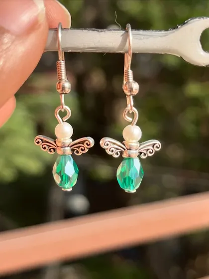 These adorable angel earrings are made with green crystal beads and pearls. A sweet and delicate design available in multiple colors.