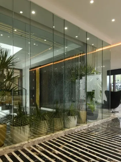 This space is framed in glass and grounded in marble. An indoor planter brings nature inside, while the striped marble flooring and glass partitions create a sense of modern luxury and transparency.