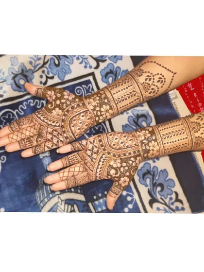 This is a classic example of bridal henna for both hands, reaching the mid-forearm. The design features traditional Indian mehndi patterns with careful attention to symmetry.