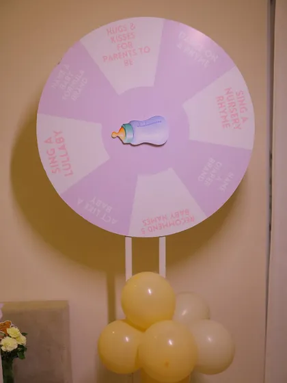 An interactive game for the baby shower guests. This custom "spin the wheel" game includes fun prompts like "Sing a Lullaby" and "Recommend Baby Names," getting everyone involved in the celebration.