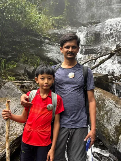 Trekking is for all ages. Here's a father and son duo, fully equipped with trekking poles, enjoying their adventure near a waterfall on the Netravati trail.