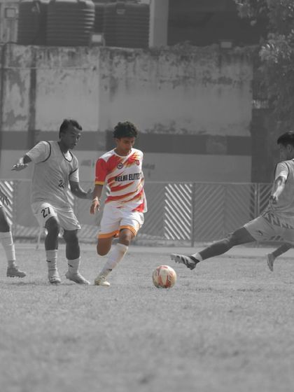 A player in our red and white kit skillfully maneuvering the ball under pressure from multiple opponents during a competitive match.