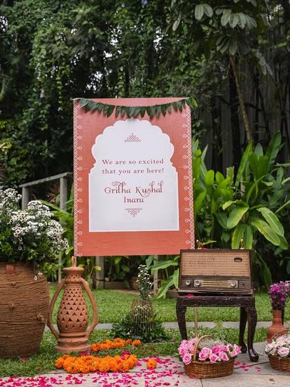 A charming welcome vignette for a naming ceremony, featuring a custom sign, a vintage radio, and terracotta pots. This setup, with its 1990s-inspired elements, created a nostalgic and personal touch.