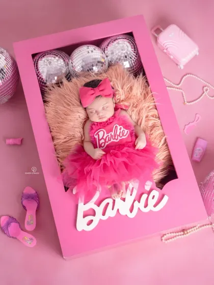 Come on Barbie, let's go party! This creative newborn shoot places a baby girl in a custom-made Barbie doll box, complete with a pink tutu and fun, glamorous accessories.