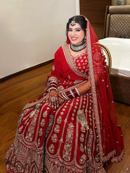Sanchi, glowing and ready for her pheras. A classic red lehenga paired with a defined eye and a warm, radiant base.