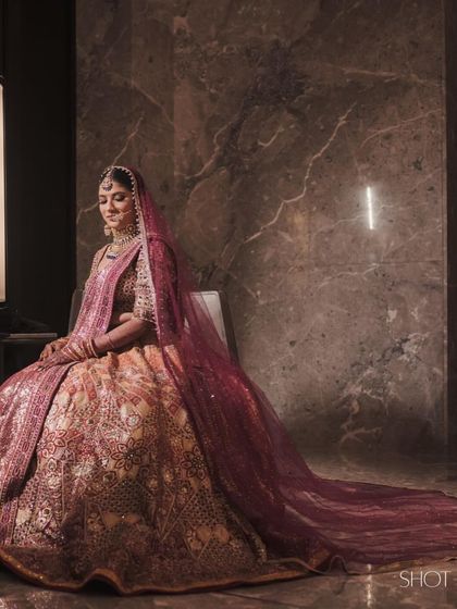 A side profile of bride Natasha, showcasing the long, flowing burgundy veil we chose to complement her Tarun Tahiliani lehenga. This adds a touch of modern drama to her traditional look.