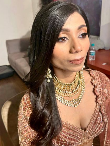 A chic and modern reception look. The makeup is focused on a clean, defined eye and a warm, brownish-nude lip that complements her earth-toned lehenga.