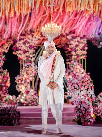 The groom, Rishabh, stands proudly before a magnificent floral arch at his Dubai wedding, a picture of calm elegance amidst the grandeur of the celebration.