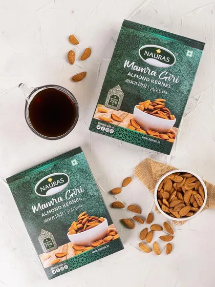 A clean, minimalist flat lay of Nauras Mamra Giri almond packaging. This e-commerce friendly style focuses on the branding and product, making it ideal for online stores.