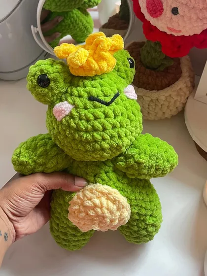 The frog prince plushie, sitting among other crochet creations. This photo gives you a sense of the variety of plush toys I can make.