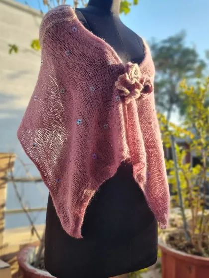 This is a delicate, lightweight poncho I knitted, featuring a beautiful lace pattern on the back and embellished with sequins and handmade flowers. It’s a versatile piece that can be dressed up or down, adding a touch of handmade elegance.