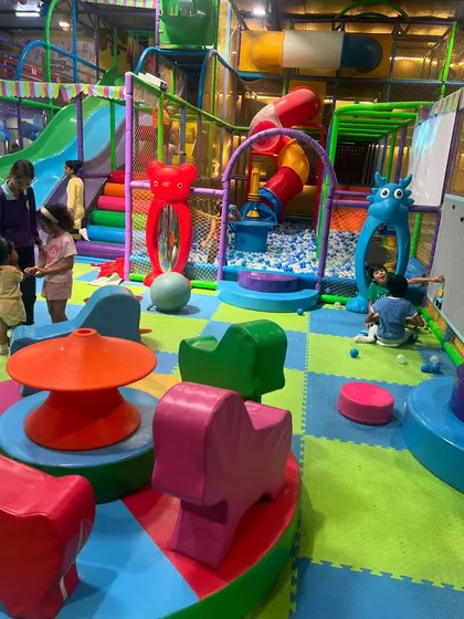 A wide view of our colorful toddler play area, featuring soft play equipment, a mini ball pit, and fun mirrors, all designed for our youngest visitors.