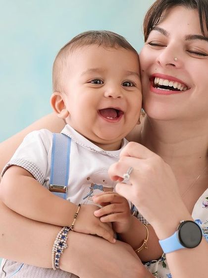The purest joy captured in a mother-and-son portrait. The light blue background adds a soft pop of color while keeping the overall feel bright, happy, and focused on their infectious laughter.