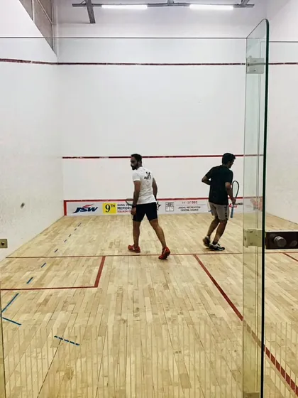 A view from behind the glass court during a competitive game at the JSW Memorial Open.