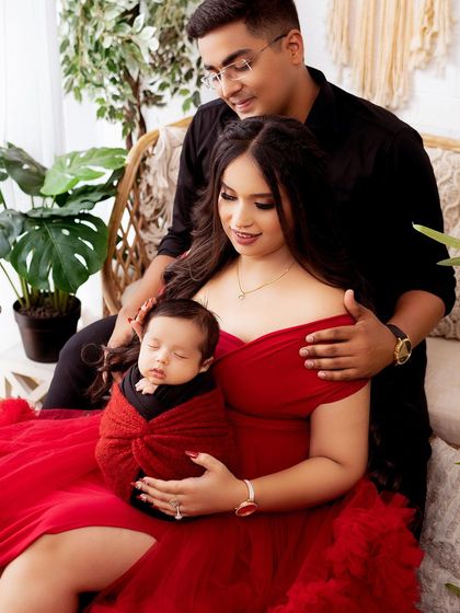 A new family of three, with the baby sleeping peacefully in mom's arms. The bold red dress adds a beautiful touch of color to this newborn session.
