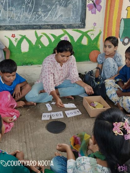 A volunteer uses number cards to teach math in a fun, interactive way at the Makkala Masti summer camp.