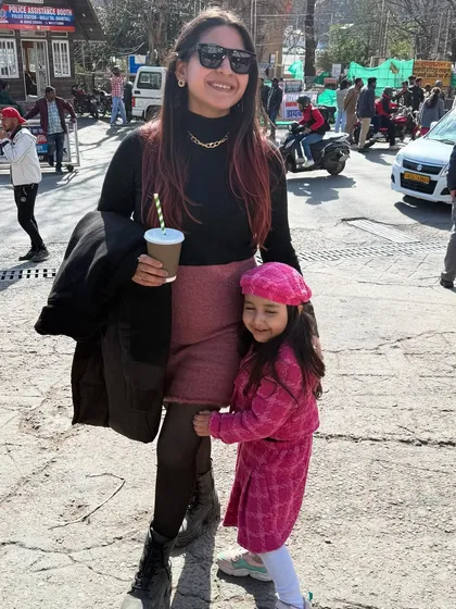 Strolling through the streets of Nainital with my daughter. I'm wearing a black turtleneck with a pink skirt and boots, a chic and practical winter look.