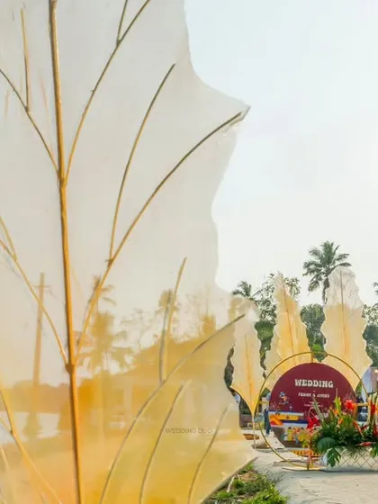 Giant, translucent leaf-like structures mark the entrance to this waterside wedding, creating an artistic and whimsical welcome for guests.