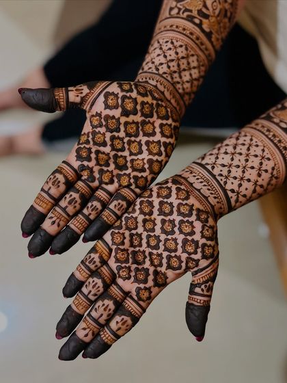 A close-up view of a detailed grid pattern, also known as 'jaali' work. This technique creates a beautiful net-like effect that is a hallmark of traditional bridal henna.