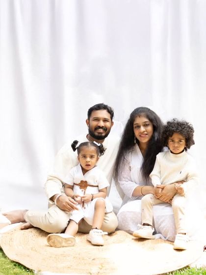 A lovely family portrait taken outdoors with a simple white backdrop. The coordinated white outfits give the photo a fresh, clean, and timeless feel.