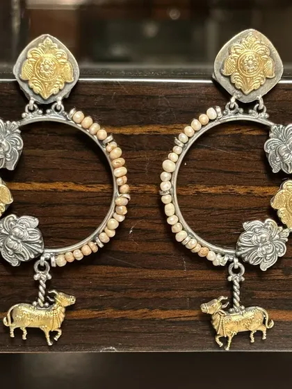 Hoops with a desi twist. These dual-tone earrings feature cow and floral motifs in gold and silver, with a beaded hoop design that adds a touch of playful elegance.