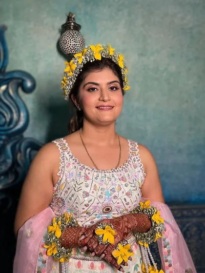A portrait of the happy bride-to-be at her Haldi. The makeup is fresh and subtle, with a soft pink lip that complements the pastel tones in her lehenga.