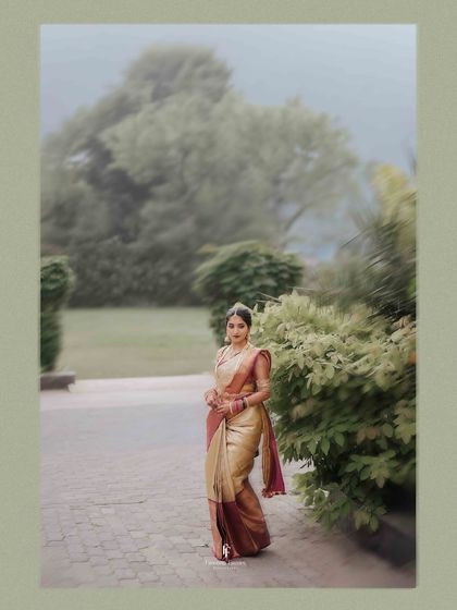 A serene portrait of a bride in a beautiful saree, standing in a misty, green landscape. This shot has a dreamy, almost painterly quality.