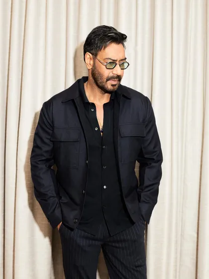 Ajay Devgn looking sharp in a layered all-black look for the 'Shaitaan' premiere, with green-tinted glasses adding a modern twist.