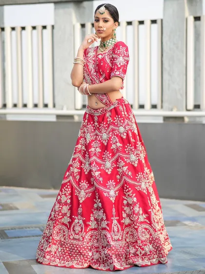 A full-length view of a stunning bridal look. This heavily embroidered red lehenga is perfectly accessorized with our green-accented choker, maang tikka, and bangles, showing how our jewellery completes your entire wedding day vision.