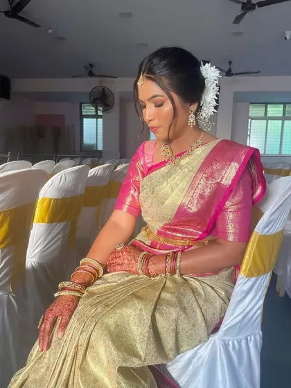 A pensive moment captured before the event. The hair is styled in a classic bun adorned with fresh white flowers (gajra).