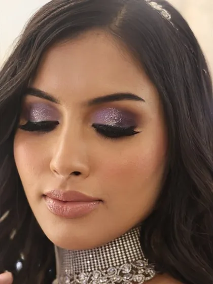 A close-up on the eye makeup, showing the sharp winged liner and the beautiful blend of purple and silver glitter.