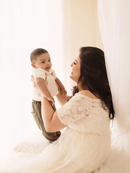 A mother lifts her baby, both silhouetted against a bright, airy background. This creates a beautiful, high-key image filled with light and love.