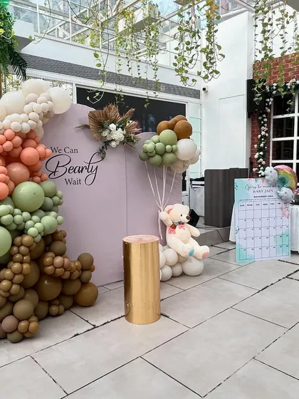 This wide shot shows the decor in a bright, airy venue, highlighting how our designs can transform any space. The setup includes the main backdrop and a guest activity board.