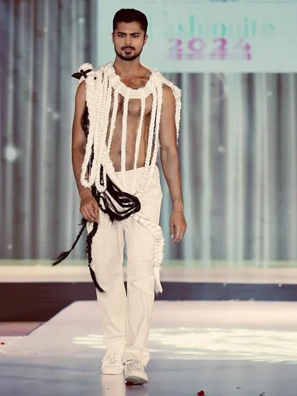 A full-length view of the woven runway piece, demonstrating how it moves and interacts with the body during the walk.